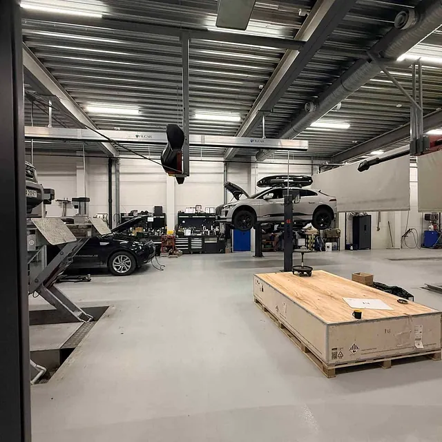 Moderne verksted med biler på løftebukker og teknisk utstyr klart til service.