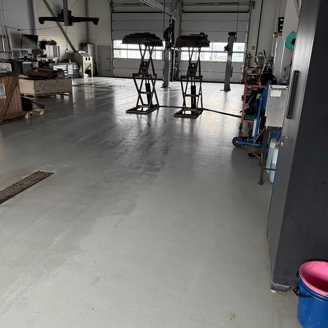 Tomt verkstedgulv med løftebukker, verktøy og godt opplyst arbeidsområde.