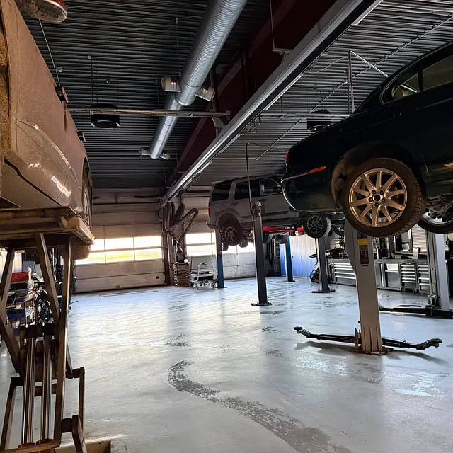 Verksted med flere kjøretøy løftet og organisert arbeidsplass for reparasjon.
